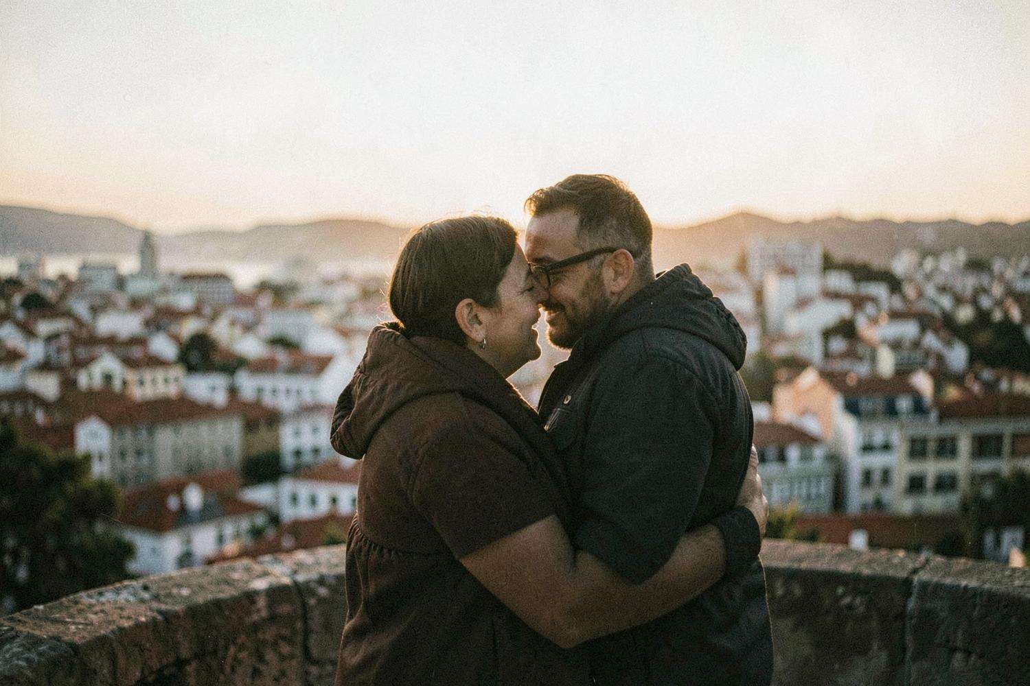 A couple holding each other at a Lisbon viewpoint at sunset