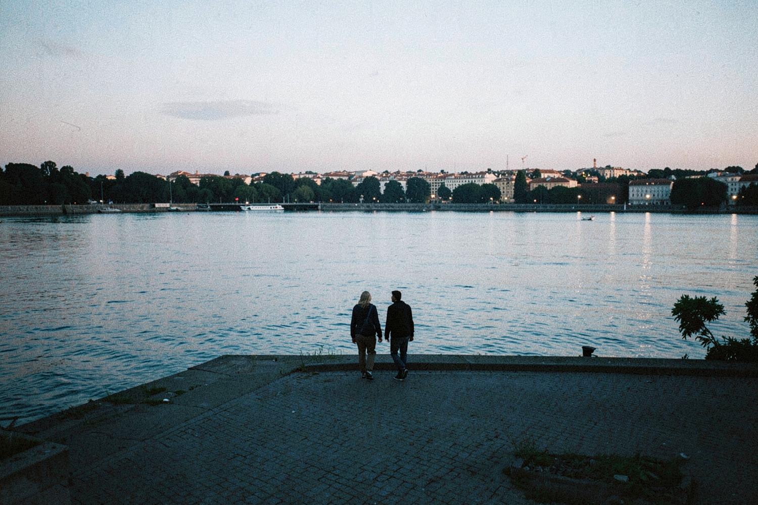 A couple walking along the riverfront at dusk